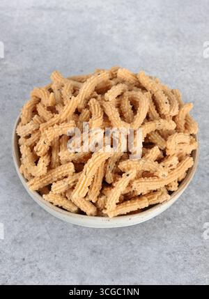 Stuzzichini indiani a base di farina di riso e spezie su sfondo grigio. Vista dall'alto. Cibo indiano. Foto Stock