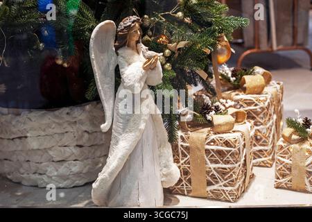 Statuetta di un angelo che tiene un uccello vicino a un albero di Natale. Natale Foto Stock
