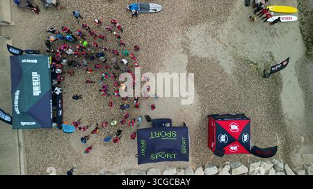 Evento di stand up paddleboard con concorrenti, tavole e spettatori sulla spiaggia di Dorset, Inghilterra, vista dall'alto Foto Stock