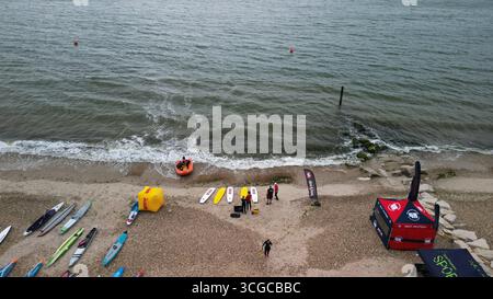 Evento di stand up paddleboard con concorrenti, tavole e spettatori sulla spiaggia di Dorset, Inghilterra, vista dall'alto Foto Stock