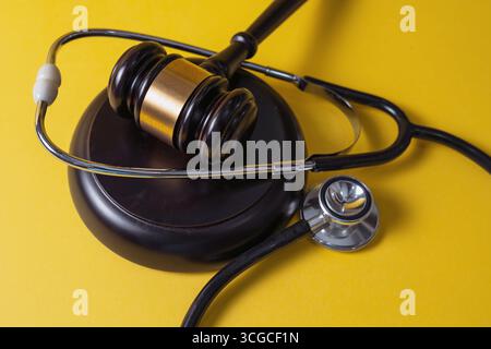 Martelletto con stetoscopio su sfondo giallo. Legale e medica. Foto Stock