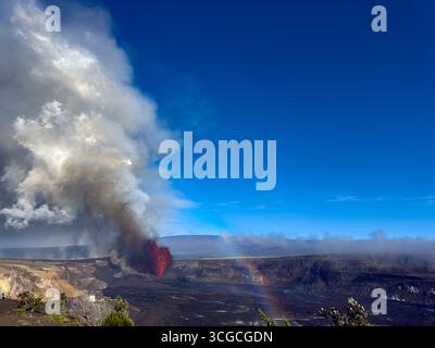 Un debole arcobaleno si forma mentre una fontana di lava calda spara dal cratere Halemaumau, liberando nuvole di cenere, vapore e gas vulcanici, Hawaii, Stati Uniti Foto Stock