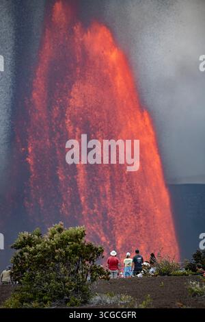 I visitatori si riuniscono in un punto panoramico per ammirare le fontane di lava calda che si estendono a 1000 metri dal cratere Halemaumau, dal vulcano Kilauea, dall'HVNP, dall'Isola delle Hawaii, Stati Uniti Foto Stock