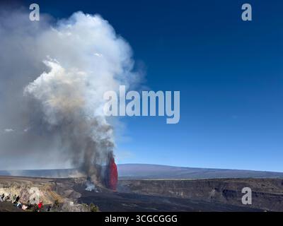 Gli osservatori fiancheggiano il bordo del cratere mentre una fontana di lava calda spara a 1200 metri dal cratere Halemaumau, con Mauna Loa sullo sfondo, HVNP, Hawaii, Stati Uniti Foto Stock