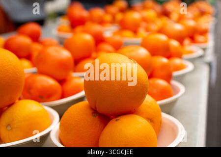Una vista di diverse piccole piramidi di arance ombeliche in mostra su un tavolo presso un mercato agricolo locale. Foto Stock
