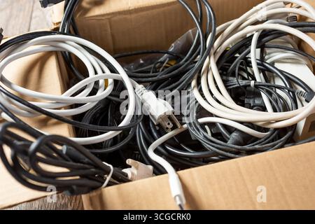 Vista di una scatola di cartone piena di computer e cavi elettronici. Foto Stock