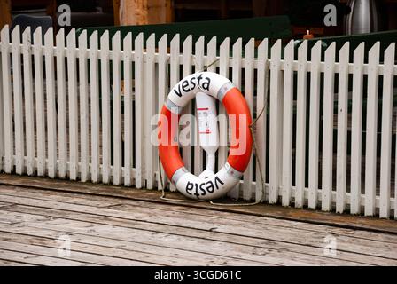 Undredal, Norvegia - 17 agosto 2013 - salvagente bianco e arancione su molo in legno con sfondo bianco recinzione. Foto Stock