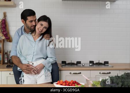 Felice coppia romantica abbracciando in cucina moderna, simboleggiando l'amore, legame familiare, stile di vita sano, cibo biologico, emozioni brillanti, insieme, a Foto Stock