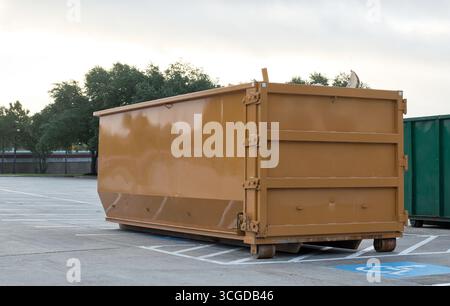 Cestino industriale per il noleggio di cassoni ribaltabili in un parcheggio commerciale, salta per la rimozione dei rifiuti marrone. Foto Stock
