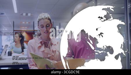 Donna che studia in camicetta rosa con notebook da lettura in un moderno ufficio, con rivestimento digitale a globo Foto Stock