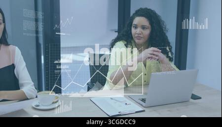 Analisi di grafici di dati fluttuanti donna con camicetta gialla che scrive su un laptop argento nella sala conferenze Foto Stock