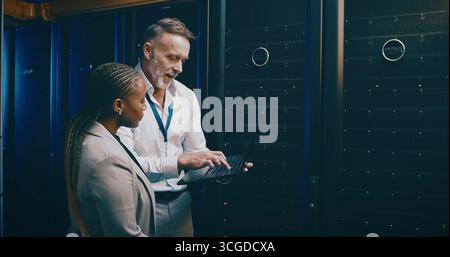 Notebook, team e persone nel data center per discussioni, aggiornamenti di sistema o IT. Collaborazione, computer e ingegnere nella sala server per la rete Foto Stock