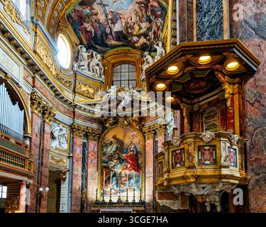 Pulpito barocco e altare maggiore riccamente decorato nei Santi Ambrogio e Carlo al corso, Roma, Italia. Foto Stock
