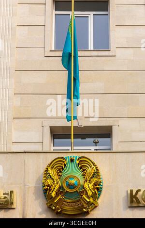 Almaty, Kazakistan, 14.02.22. Emblema nazionale del Kazakistan, stemma circolare dorato e bandiera nazionale del Kazakistan. Foto Stock