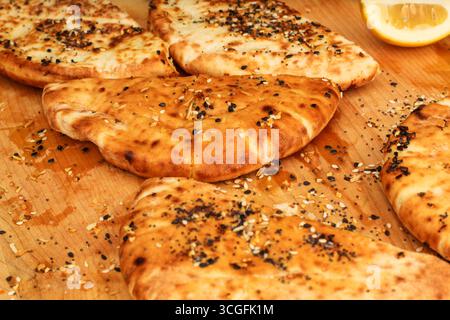 Pane Pita fresco su tagliere in legno con olio d'oliva e condimento Foto Stock