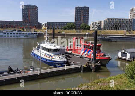 Due battelli di soccorso ormeggiati, un motoscafo dei vigili del fuoco e un battello della polizia, siedono sul fiume Waal a Nijmegen con appartamenti moderni sullo sfondo. Nijmegen, Netherla Foto Stock