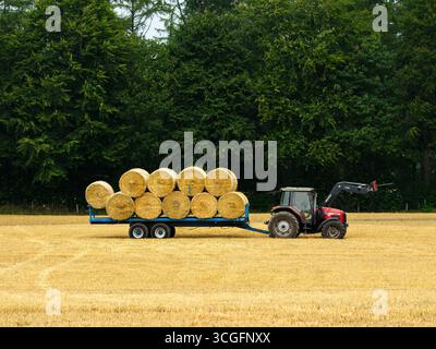 Trattore e caricatore frontale parcheggiati nel campo (vista laterale). Balle di paglia circolari non imballate raccolte caricate al momento del raccolto - Farnley, North Yorkshire, Inghilterra Regno Unito. Foto Stock