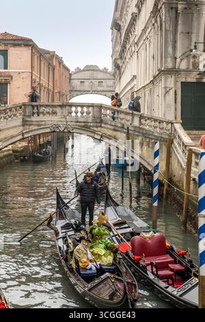 Venezia, Italia - 7 febbraio 2025: Un gondoliere naviga con i turisti durante il carnevale lungo un canale a Venezia vicino al ponte Soupirs, Italia. Foto Stock