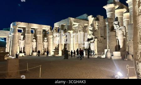 Luxor, Egitto - 9 febbraio 2025: Vista notturna del colonnato illuminato e delle colossali statue del Tempio di Luxor in Egitto, con i visitatori che esplorano l'antico Foto Stock