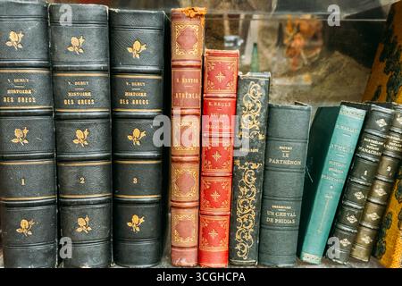 Primo piano di antichi libri francesi con legature ornate esposte su uno scaffale del mercato delle pulci. Reperti del mercato delle pulci, vendita al dettaglio vintage, acquisti di seconda mano Foto Stock