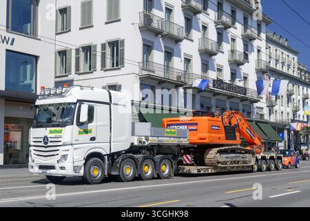 Lucerna - veicolo per il trasporto pesante 8X4 Mercedes-Benz Actros 4163 con escavatore cingolato arancione CAT 340 su un rimorchio a pianale ribassato Goldhofer su strada. Foto Stock