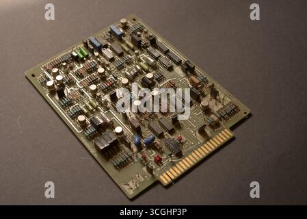 Primo piano di una vecchia scheda elettronica che mostra componenti vintage come resistori, condensatori, diodi e circuiti integrati. Tecnol isolato Foto Stock