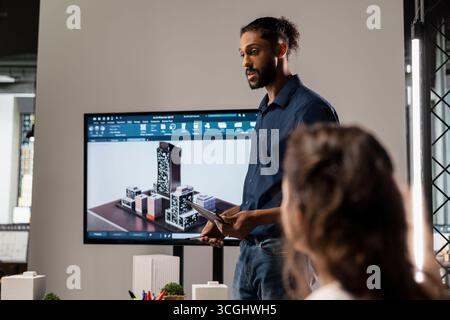 Sviluppatore urbano del Medio Oriente che presenta ai colleghi il piano generale dei progetti, tenendo un briefing sulle idee di progettazione delle costruzioni e sulla pianificazione urbana. Lavori di riqualificazione immobiliare. Foto Stock