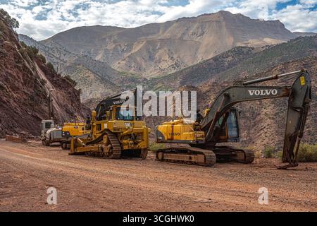 Macchinari per l'edilizia pesante, tra cui escavatore Volvo e bulldozer CAT su un progetto stradale di montagna nelle montagne dell'Atlante in Marocco Foto Stock