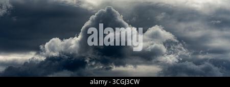 Nuvole scure e a strati si accumulano nel cielo, le loro texture dense e i toni drammatici suggeriscono una tempesta in avvicinamento. Formato panorama Foto Stock