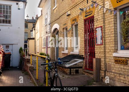 Una strada stretta a Saffron Walden, Essex, con edifici in mattoni, una bicicletta e negozi. Foto Stock