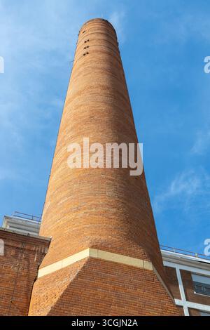 Vista ad angolo basso a struttura completa di un camino industriale in mattoni del tardo XIX secolo, alla luce del sole con cielo blu Foto Stock