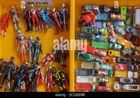 Ipoh, Malesia – 17 agosto 2025: Un variopinto assortimento di giocattoli di seconda mano, tra cui action figure, personaggi dei cartoni animati e oggetti da collezione Foto Stock