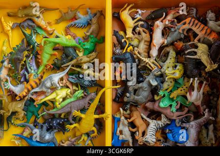 Ipoh, Malesia - 17 agosto 2025: Una foto in alto che mostra una varietà di animali in plastica e figure di dinosauro in miniatura impilati insieme in un bidone giallo A. Foto Stock