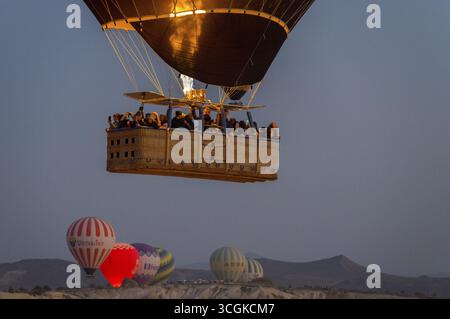 Una mongolfiera con passeggeri nel cesto galleggia sotto il cielo mattutino, il Parco Nazionale di Goereme, il Parco Nazionale di Goereme Tarihi Milli ParkIJ, la Provincia di Nevsehir Foto Stock