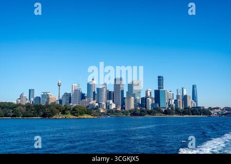 Lo skyline di Sydney presenta moderni grattacieli e l'iconica Sydney Tower, vista dall'acqua. I parchi verdi contrastano con l'architettura urbana di un Foto Stock