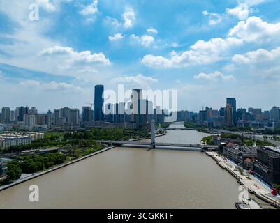 Vista panoramica della città di Ningbo in Cina con un ampio fiume che scorre attraverso moderni grattacieli e ponti sotto un cielo blu. Foto Stock
