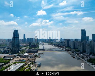 Una vista aerea della città di Ningbo in Cina mostra edifici alti, un ampio fiume e un lungo ponte sotto un cielo blu brillante. Foto Stock