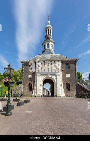 La storica porta Zijlpoort di Leida con un arco centrale e una torre dell'orologio, circondata da una piazza lastricata in una giornata di sole. Foto Stock