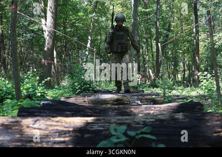 Un fanteria del battaglione operativo della 13a Brigata operativa della Guardia nazionale Ucraina della Khartiia si mette sui tronchi lungo la rotta ad ostacoli durante una sessione di addestramento al tiro, regione di Charkiv, Ucraina, 28 agosto 2025. (Foto di Viacheslav Madiievskyi/Ukrinform) Foto Stock