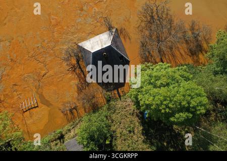 Vista aerea della casa del villaggio che affonda nel mezzo del lago di decantazione delle miniere tossiche Foto Stock