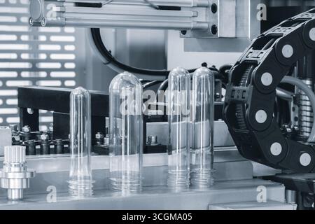 Preforme in plastica PETG per la produzione di bottiglie sul nastro trasportatore prima della pressa per soffiaggio a caldo Foto Stock