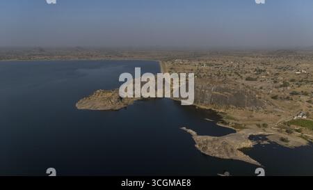 Veduta aerea del netto contrasto tra le acque blu scuro del bacino idrico e il terreno accidentato e soleggiato, Gubi, Bauchi, Nigeria. Foto Stock