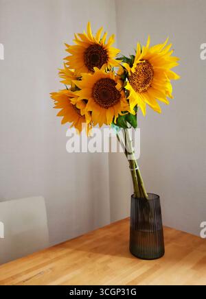 Bouquet di girasoli gialli in un vaso di vetro su un tavolo di legno Foto Stock
