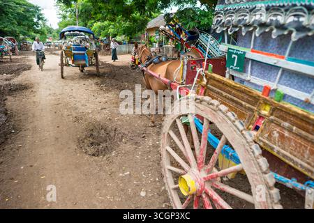 Gite turistiche a cavallo e in carrozza Inwa Amarapura Myanmar // INWA (anche conosciuta come Ava), Amarapura, Myanmar - le giostre turistiche a cavallo e in carrozza sono un mezzo di trasporto primario per i visitatori che esplorano l'antica città. Queste tradizionali carrozze trainate da cavalli percorrono le strade sterrate della zona. Sono il modo principale per i turisti di muoversi perché non ci sono taxi o auto ammessi nella zona. Inwa, un'ex capitale reale, si trova vicino ad Amarapura nella regione di Sagaing nel Myanmar centrale (nota anche come Birmania). La zona è una destinazione popolare per le sue rovine storiche e il fascino rurale, Foto Stock