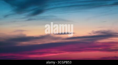 Cielo accattivante che si illumina di tonalità vivide e nuvole fluttuanti, catturando la magia di un etereo momento di tramonto. Foto Stock