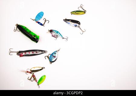 Assortimento di colorate lure da pesca, spinner e cucchiai su sfondo bianco, che rappresentano attrezzature da pesca, attrezzature da pesca e sport all'aperto Foto Stock