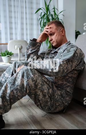 Soldato depresso seduto sul pavimento soffre di disturbo da stress post-traumatico Foto Stock