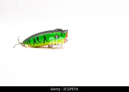 Primo piano di un vivace richiamo da pesca verde e nero con ganci alti su sfondo bianco, ideale per pesca, attrezzatura da pesca e sport all'aperto Foto Stock