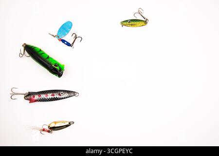 Assortimento di colorate lure da pesca, spinner e cucchiai su sfondo bianco, che rappresentano attrezzature da pesca, attrezzature da pesca e sport all'aperto Foto Stock