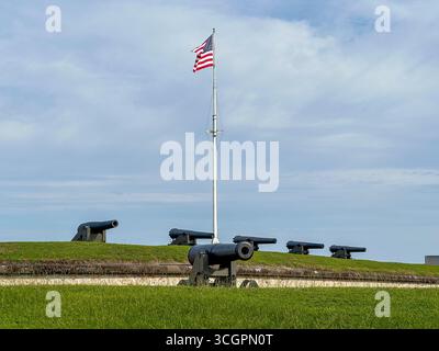 Una fila di storici cannoni di difesa costieri allinea i bastioni erbosi di Fort Macon, nella Carolina del Nord, con una bandiera americana Foto Stock
